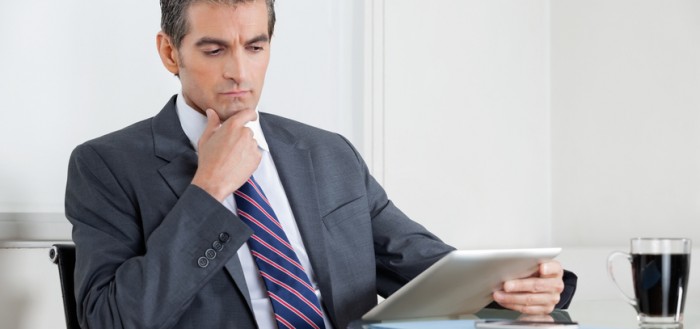 Contemplative Businessman Using Digital Tablet In Office