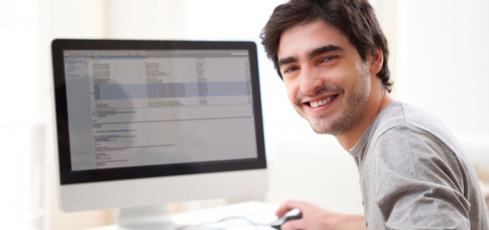 View of a Young smiling man in front of computer
